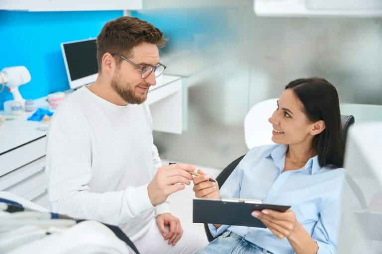 Professional stomatologist offering to sign insurance documents to female patient