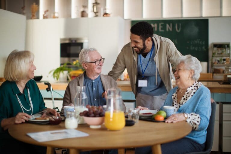 Group of cheerful seniors enjoying breakfast in nursing home care center