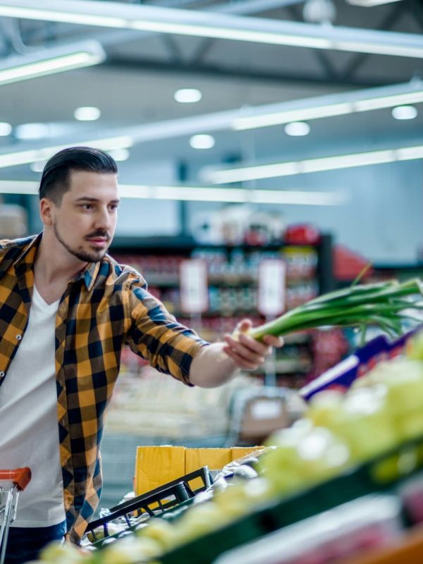 Young handsome man in a supermarket grocery shopping